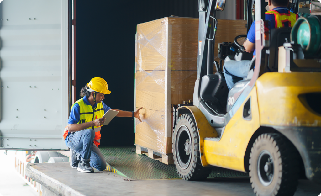 a man in a hard hat and vest pointing at a forklift