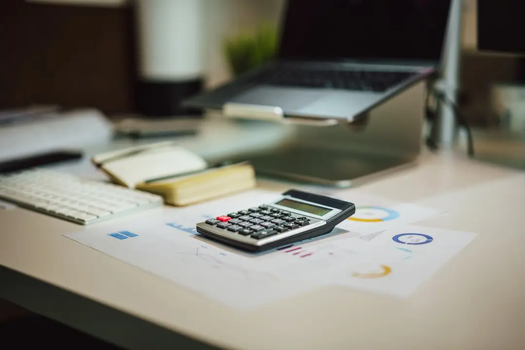 A calculator next to a keyboard and a laptop